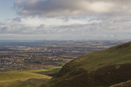 Green hillside overlooking Edinburgh's suburbs and the Firth of Forth beyond
