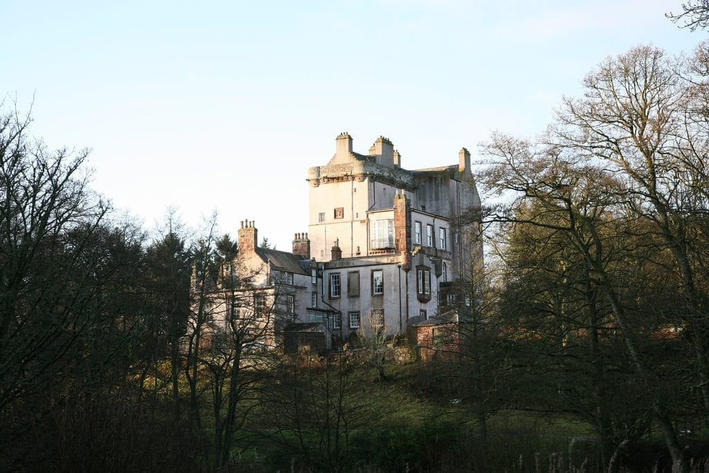 Delgatie Castle's tower rising above bare winter trees.