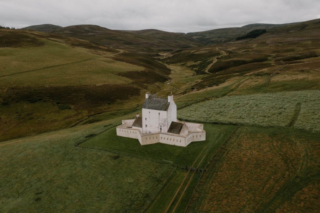 Whitewashed tower house with star-shaped walls sits amid rolling green hills