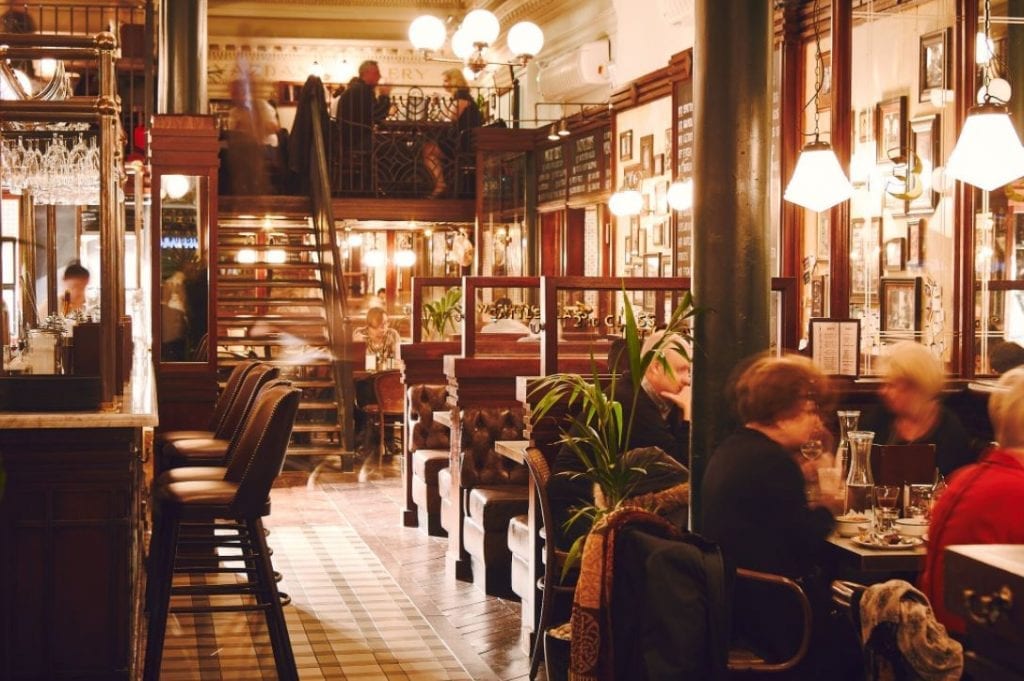 The busy dining room with its gallery above and lamps glowing.