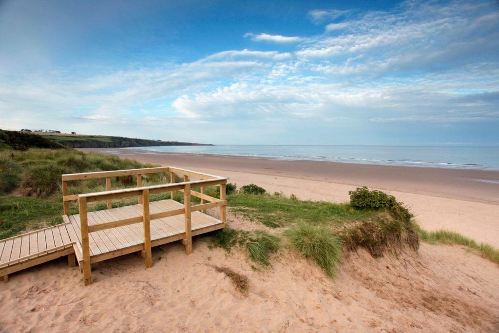 Wooden viewing platform overlooking dunes and a wide sandy beach
