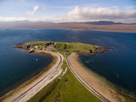 Aerial view of a tidal island linked to the shore by twin sandy causeways