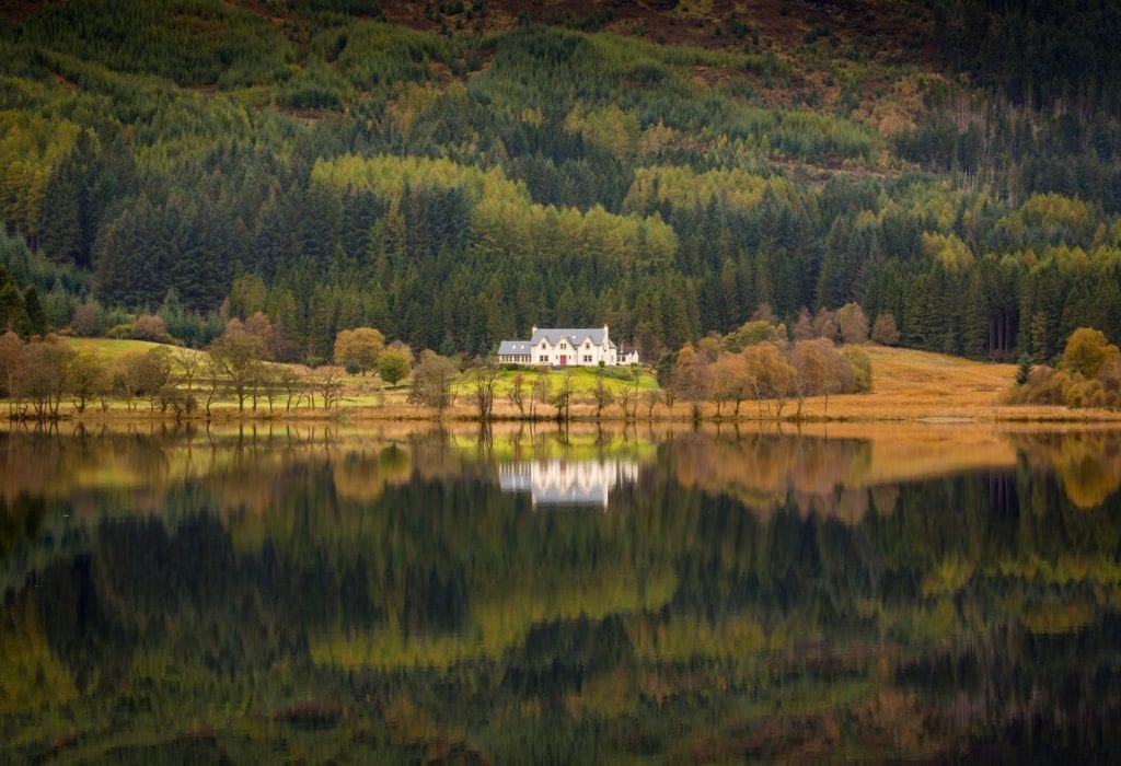 Loch Chon among autumn woods, a white house on the far shore.