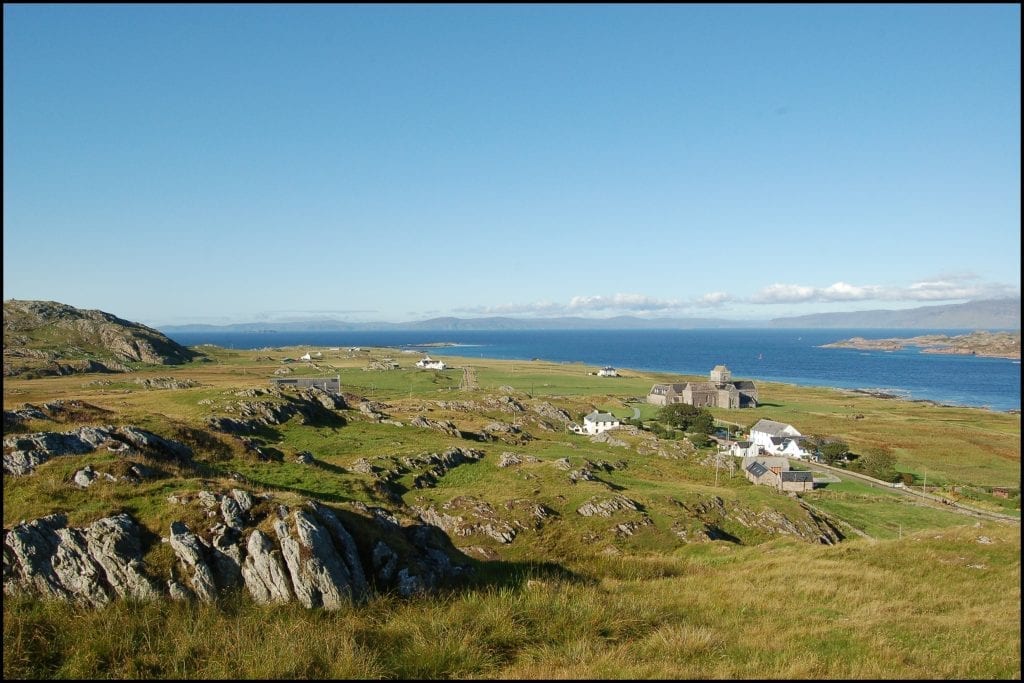 Scattered white cottages and a ruined church on a grassy coastal headland