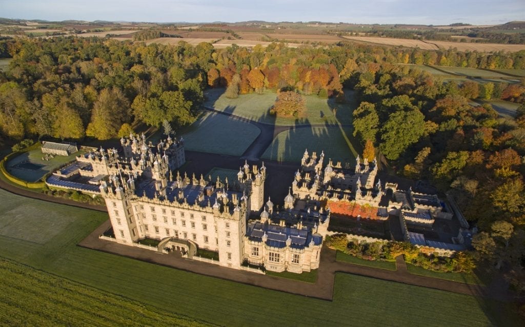 Aerial view of Fyvie Castle's turreted grounds surrounded by autumn woodland and fields