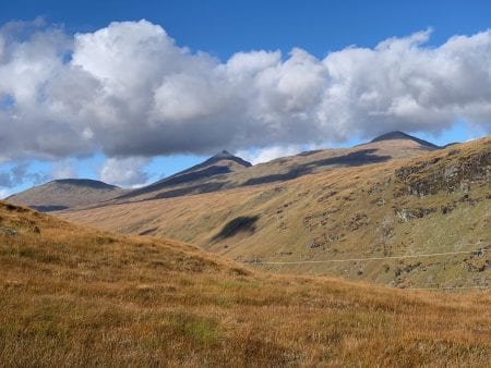Ben Oss and its neighbours above golden grass under big clouds.
