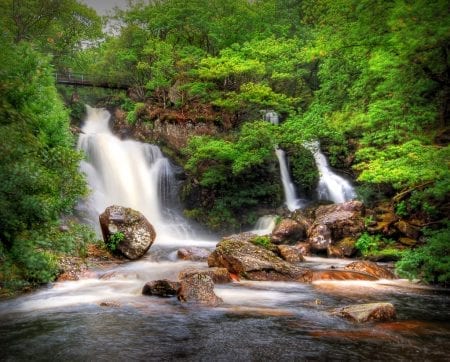 The Inversnaid falls pouring through green woods into Loch Lomond.