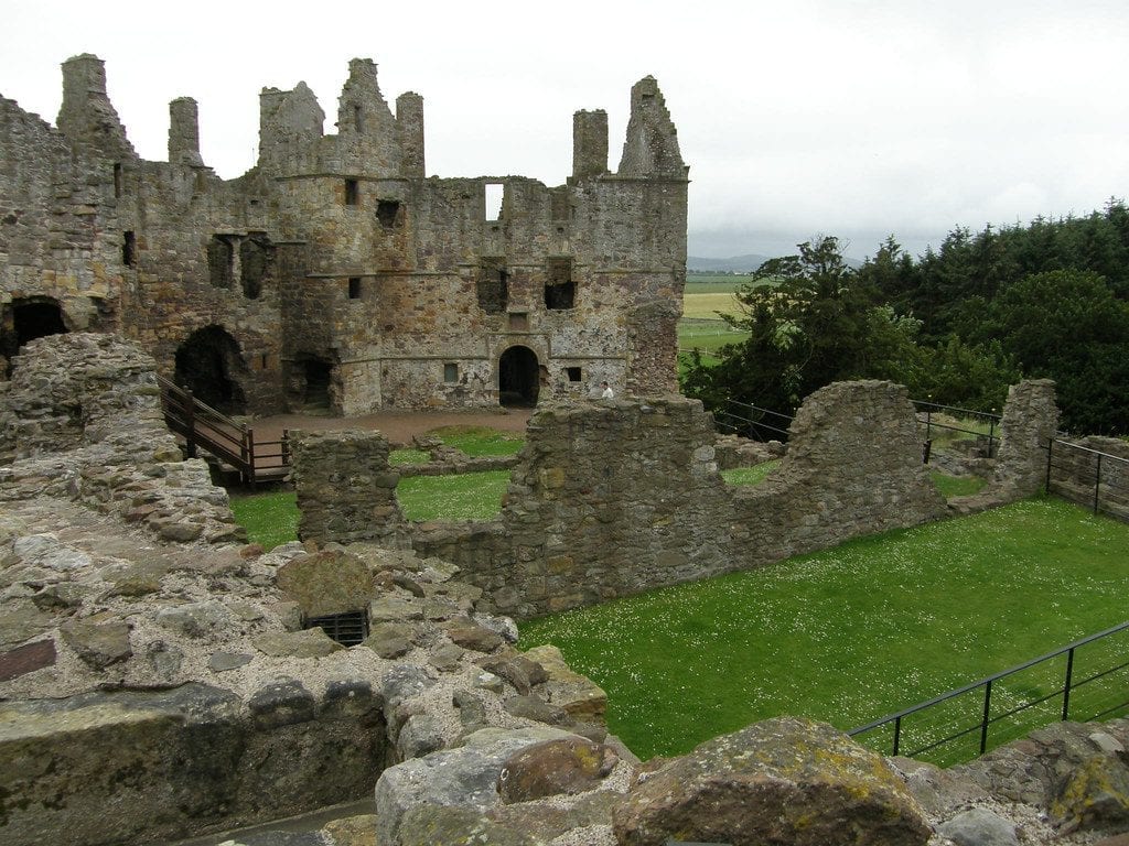 Ruined stone walls and towers surround a grass courtyard at Dunbar Castle