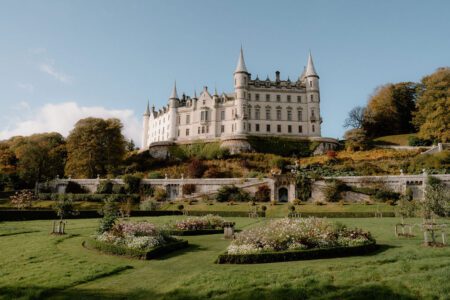 Turreted white castle overlooking manicured gardens with rose beds and lawns