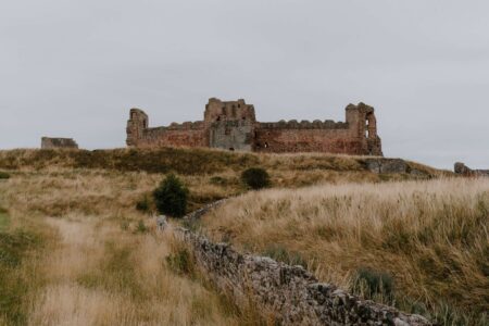 Ruined castle on a grassy hilltop behind a low stone wall