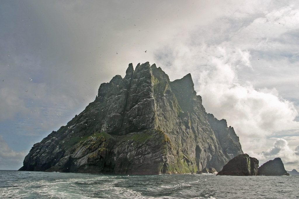 Jagged sea stack rising from the Atlantic with birds circling overhead