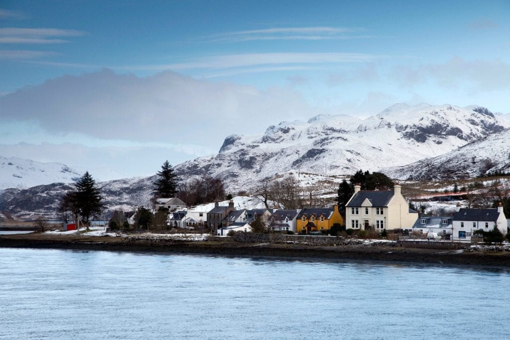 Snow on the hills above Loch Long and a line of white houses.