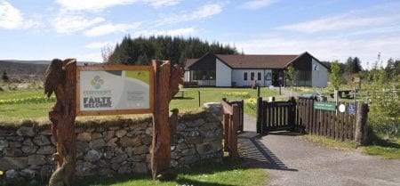 Wooden gate and "Failte Welcome" sign beside a stone wall at a visitor centre