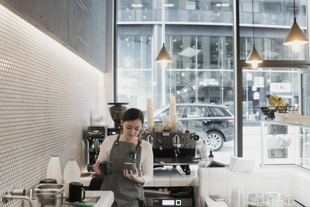 A server at the white counter with bowls ready to fill.