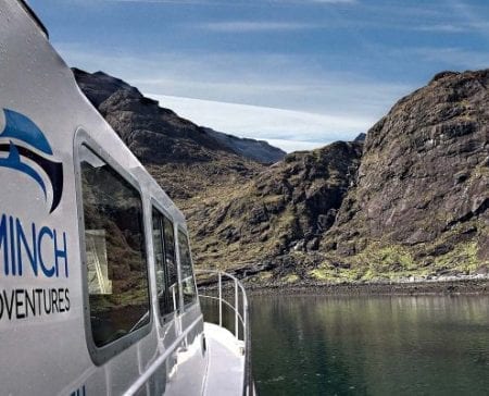 Minch Adventures boat approaching steep rocky cliffs along a narrow sea loch