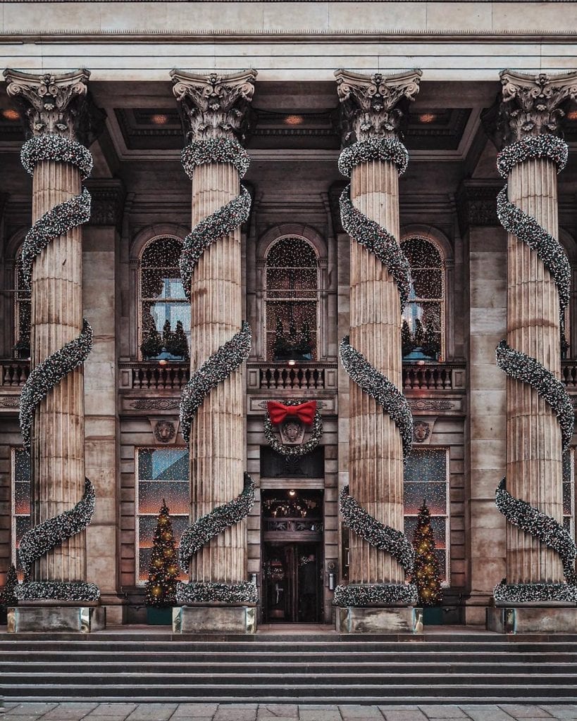 Corinthian columns wrapped in fairy lights with a red-bowed wreath at the entrance