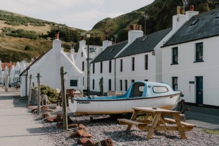 Boat named Pennan rests on the shore beside whitewashed cottages