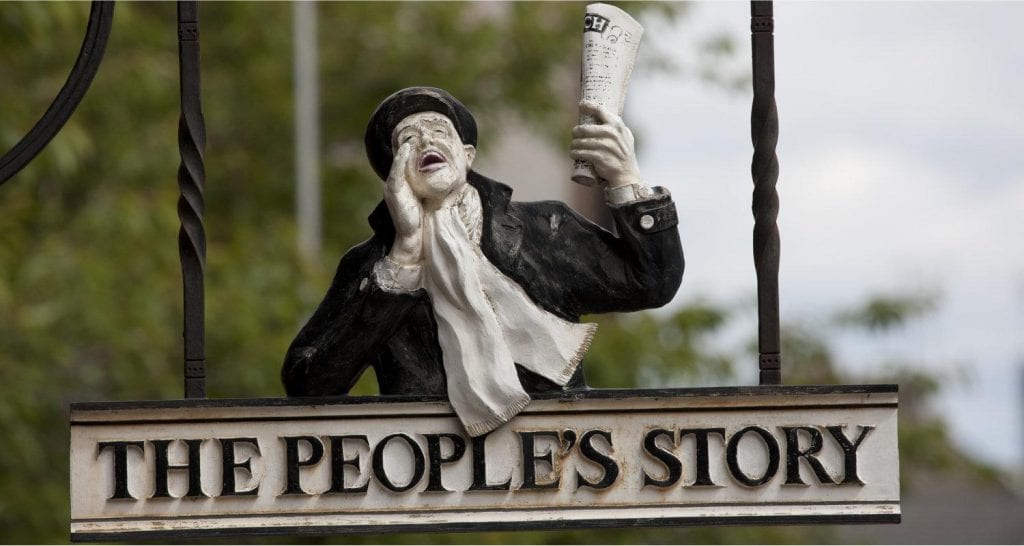 Painted figure of a newsboy shouting above The People's Story sign