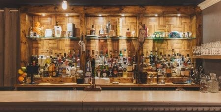 Wooden bar with glass shelves lined with spirits and beer taps