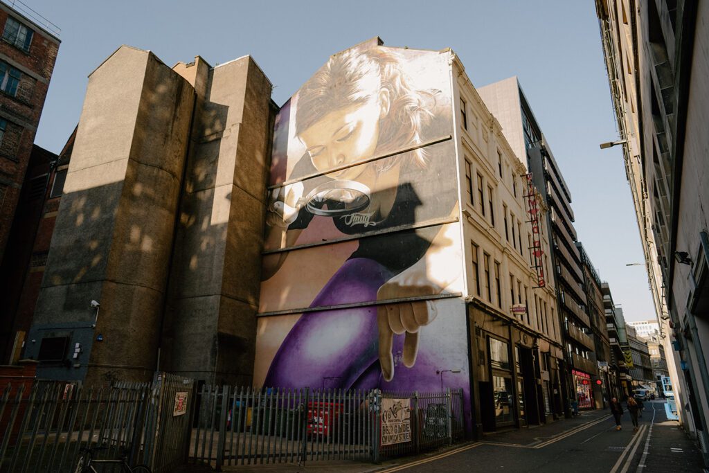 The Honey I Shrunk the Kids mural, a girl peering through a magnifying glass across a tall gable end.