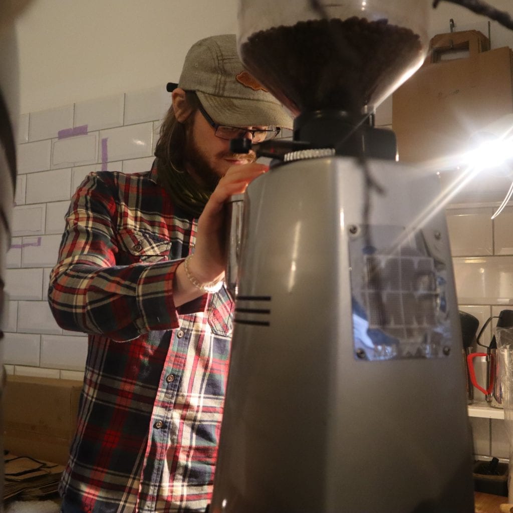 A barista grinding coffee behind the counter.