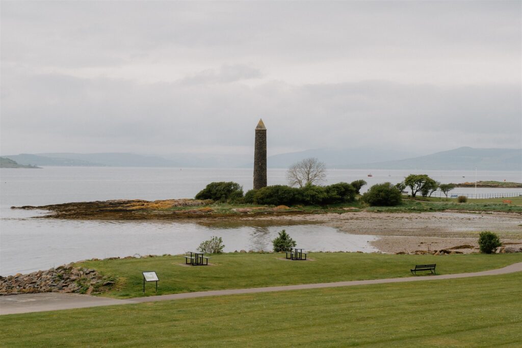 Stone tower on a headland overlooking a grey sea loch