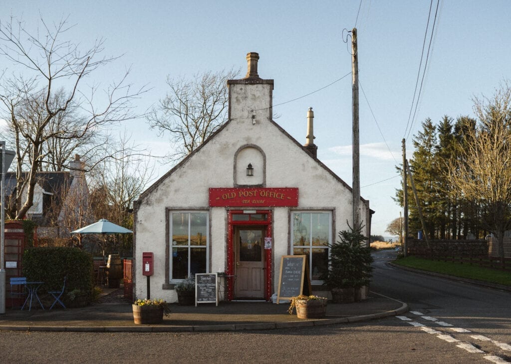 White gabled building with red door, sign reading "Old Post Office" above windows