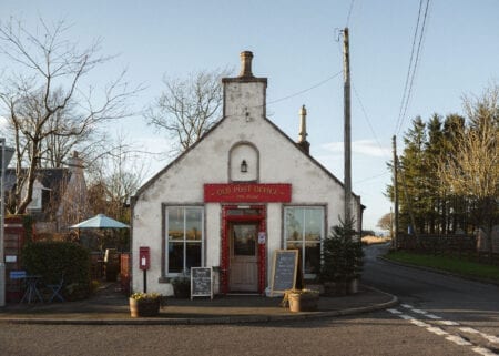 White gabled building with red door, sign reading "Old Post Office" above windows