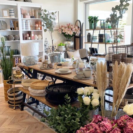 A long table of ceramics, vases and flowers.