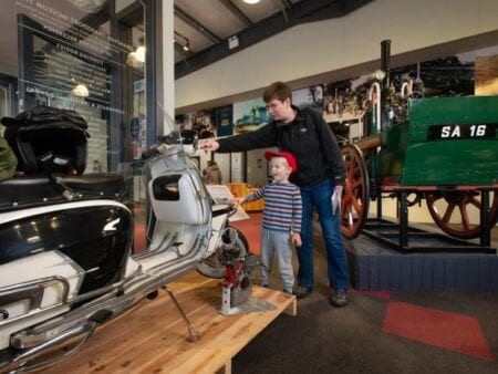 Visitors among a steam engine and old cars in the Grampian Transport Museum.
