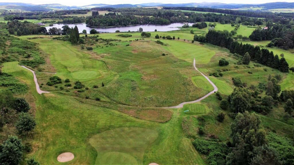 Aerial view of a golf course with fairways, bunkers and a river beyond
