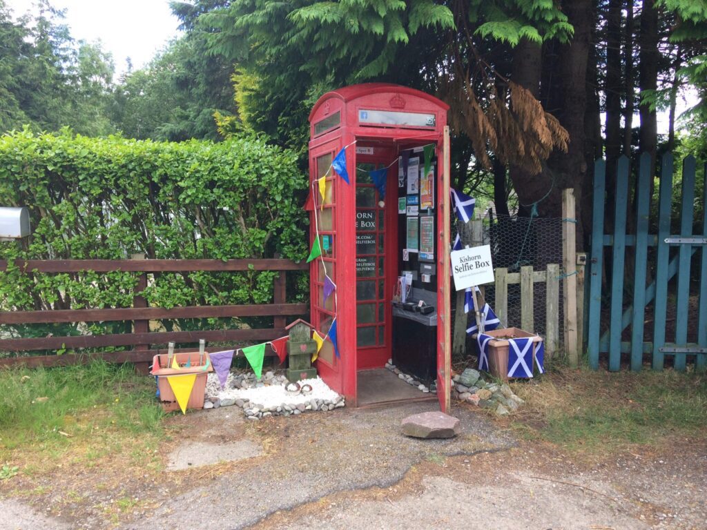 Red telephone box converted into a village book exchange, decorated with Saltire flags and bunting