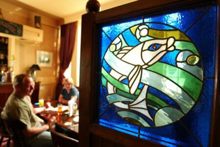 Stained glass fish design beside diners seated at a pub table