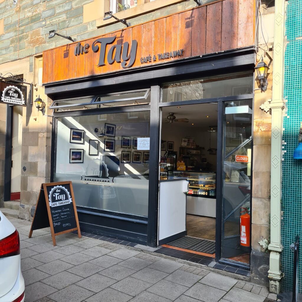 The Tay Cafe & Takeaway shopfront with framed pictures and a chalkboard menu outside
