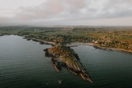 Aerial view of a rocky headland jutting into the sea near a coastal village