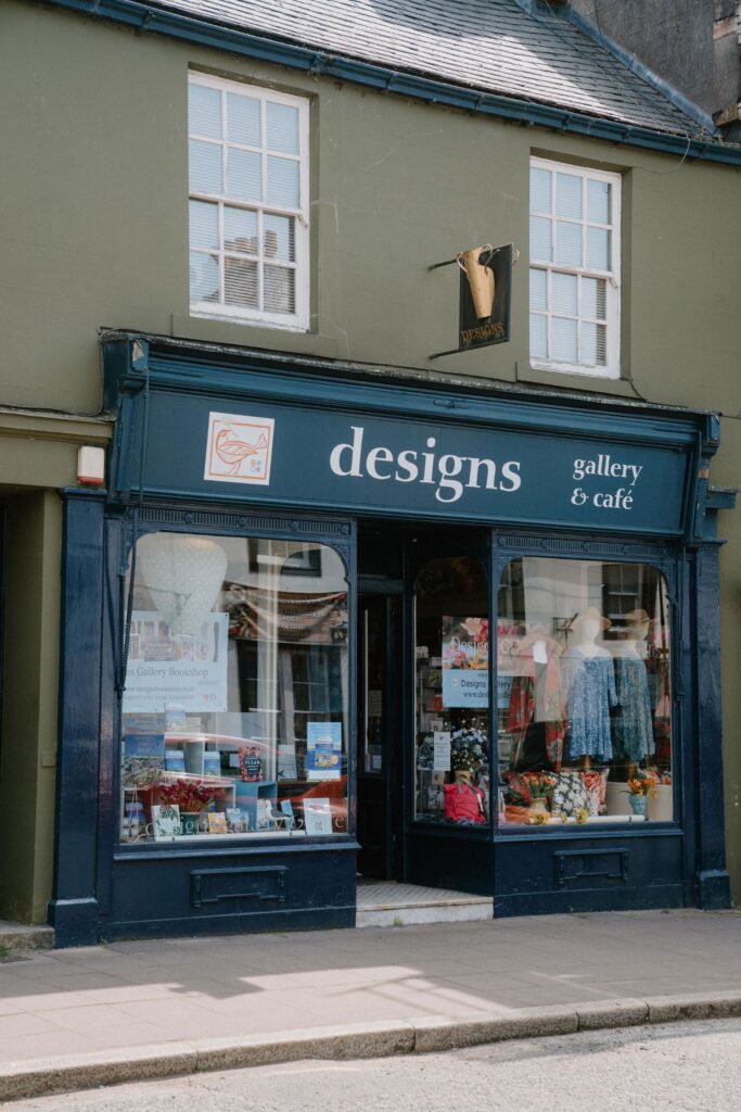 Navy-blue shopfront of Designs Gallery & Café, with display windows either side