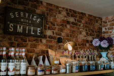Wooden shelf with jars and Monin bottles below a "Service With A Smile" sign