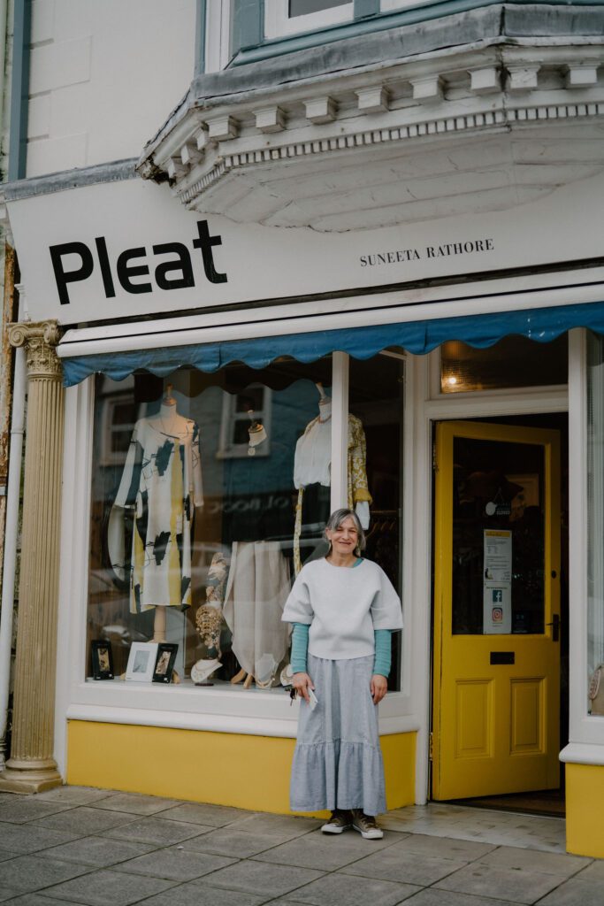 Woman stands outside Pleat, Suneeta Rathore's shop with yellow door