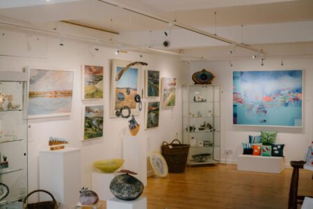 Gallery interior with framed paintings, ceramics on plinths and glass display cabinets