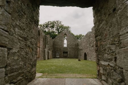 Ruined stone abbey framed by a doorway, grass filling the roofless nave