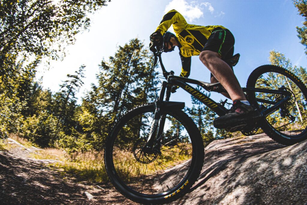 Mountain biker in yellow jersey riding down a rocky forest trail