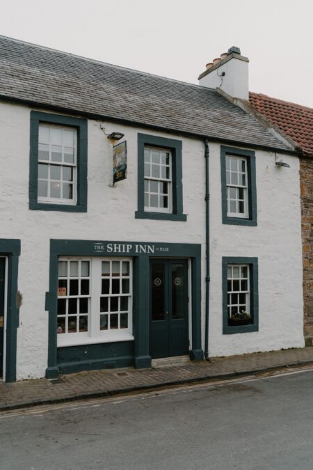 The Ship Inn's white harled frontage with dark green window frames on a quiet street
