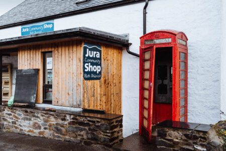The Jura Community Shop, a timber building with a red telephone box beside it in Craighouse.