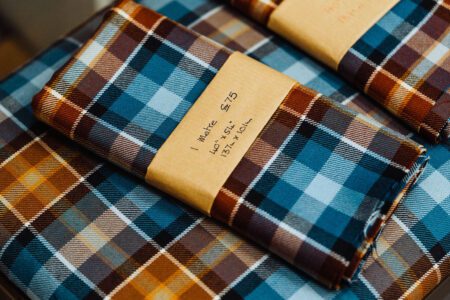 Tartan and tweed pieces made at Camella Crafts, folded on a table.