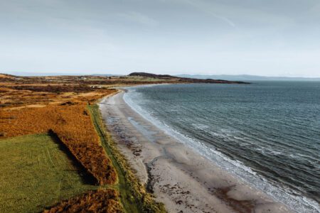 Corran Sands from above, a long curve of pale sand between the sea and the moor.