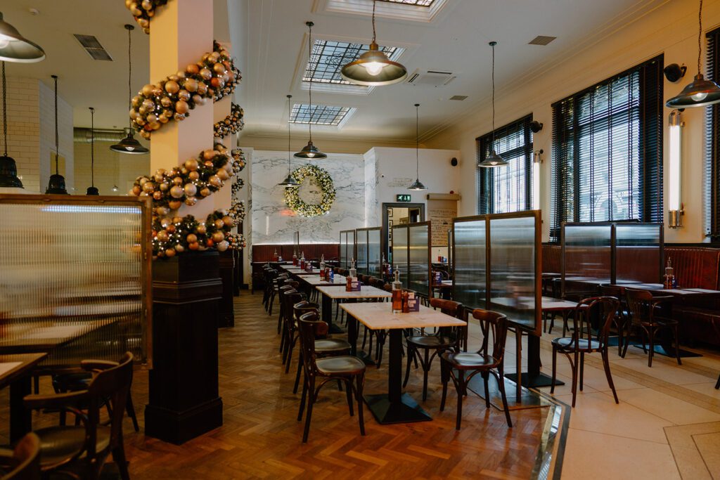 Restaurant dining room with bentwood chairs, bauble garland and hanging pendant lights