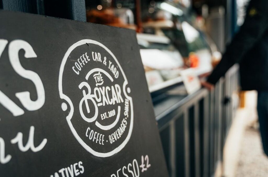 Chalkboard sign for The Boxcar Coffee Car and Yard, established 2018