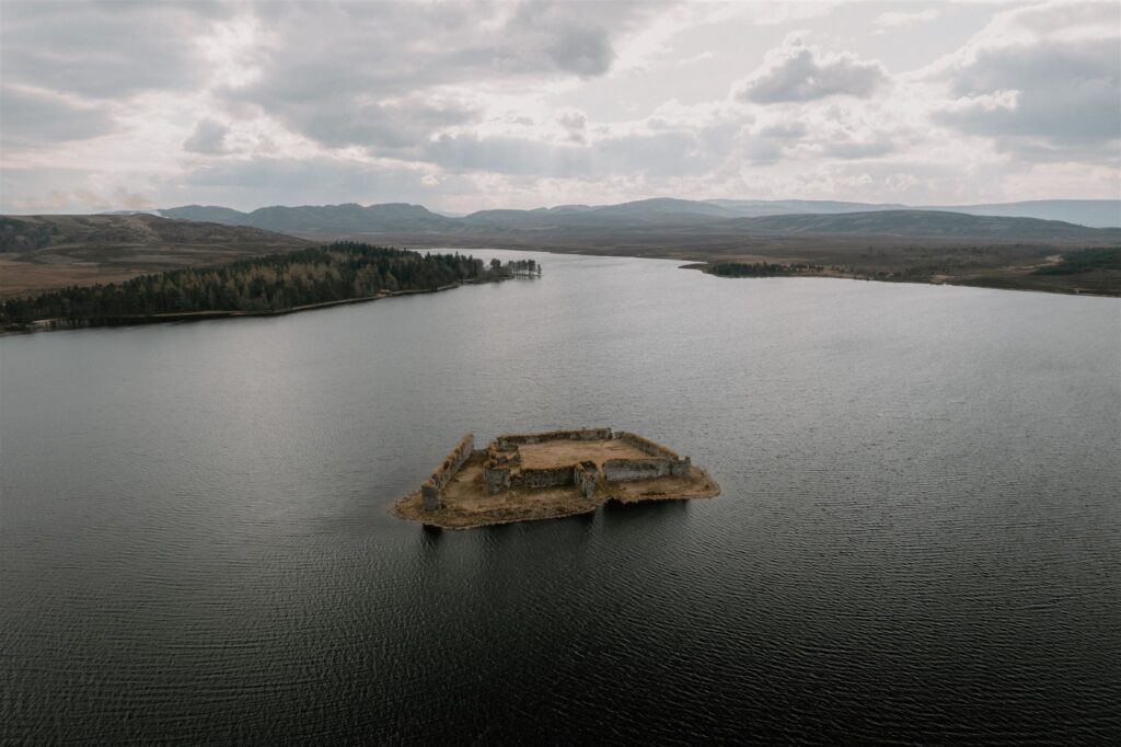 Ruined castle on a small island in a loch surrounded by hills