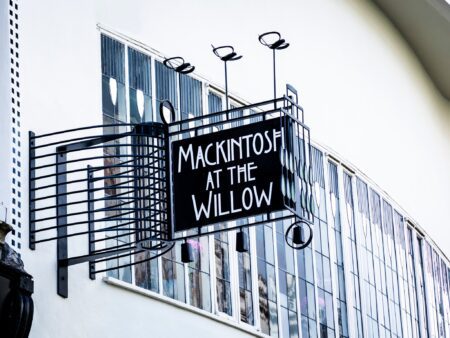 The Mackintosh at the Willow sign in black ironwork against the white front of the tearooms.