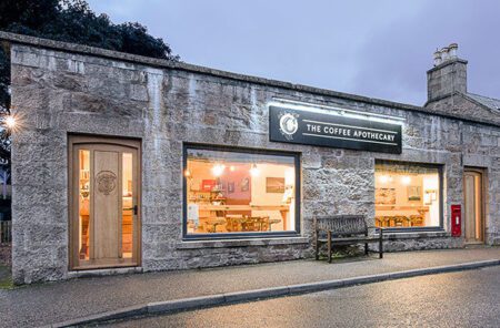 The Coffee Apothecary's granite café in Udny at dusk, its windows lit.